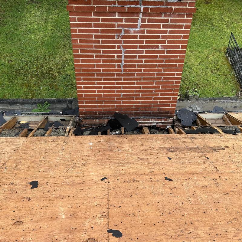 Roof decking removal near chimney base on wooden roof