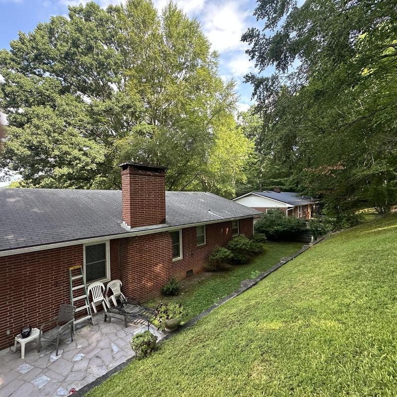Asphalt shingle roof on brick house with patio chairs
