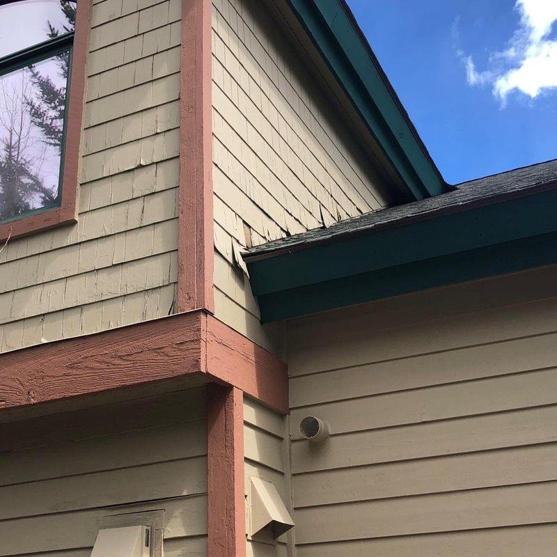 Asphalt shingle roof with damaged siding on house corner