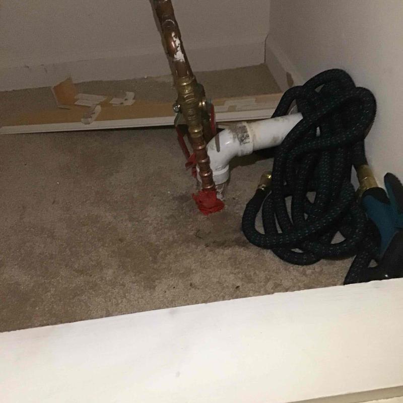 Water supply valve and drain pipe with garden hose nearby