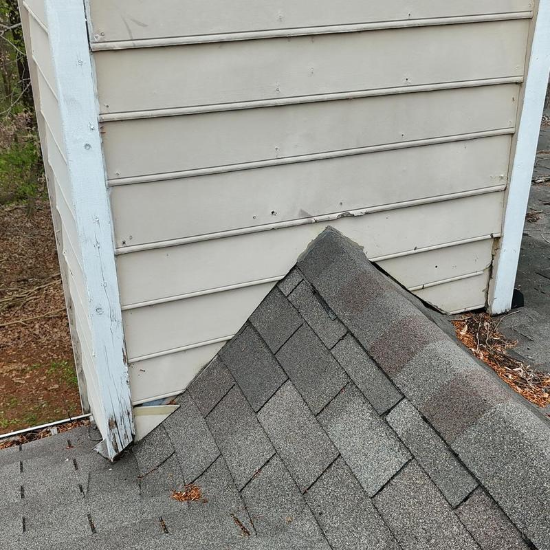 Wood siding damage near shingled roof corner