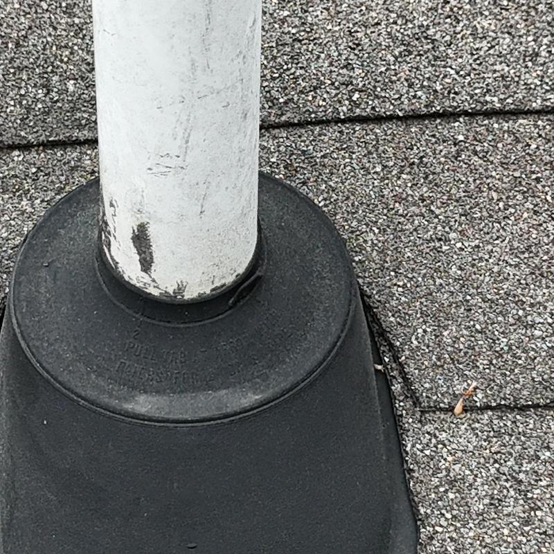 Roof pipe boot with worn seal on asphalt shingles