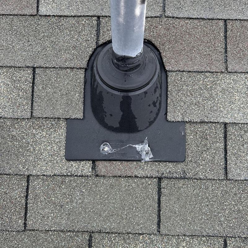 Roof pipe flashing with sealant on asphalt shingles