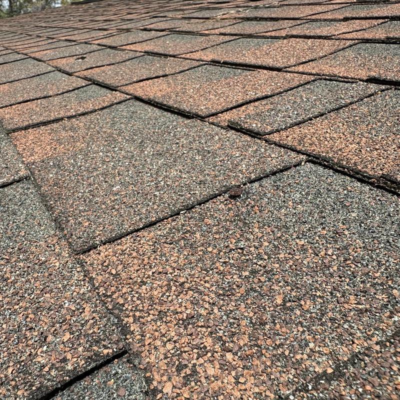 Roof shingles with visible nail pop on surface