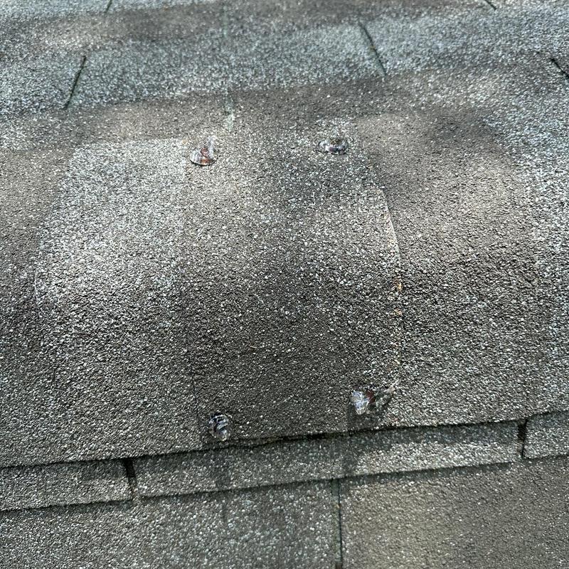 Roof shingles with exposed and rusted nails close-up