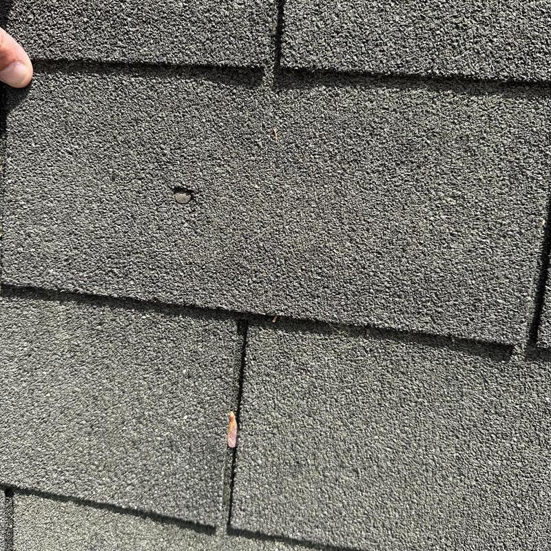 Asphalt roof shingles with nail popping defect