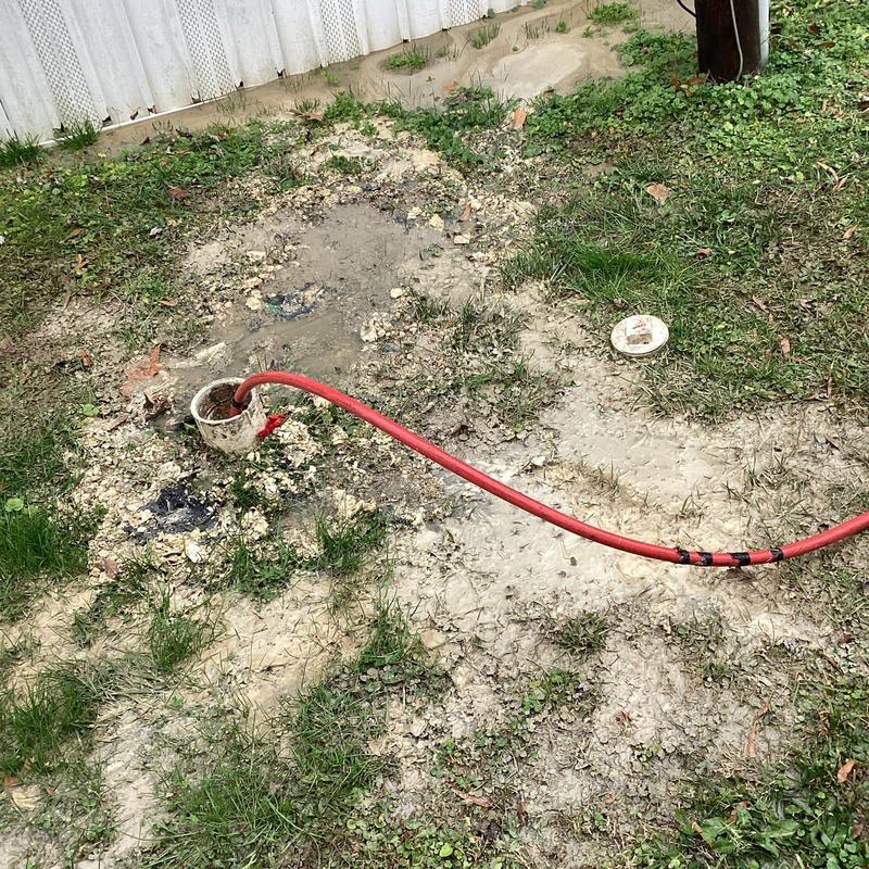 Sewer cleanout with jetting hose in muddy yard