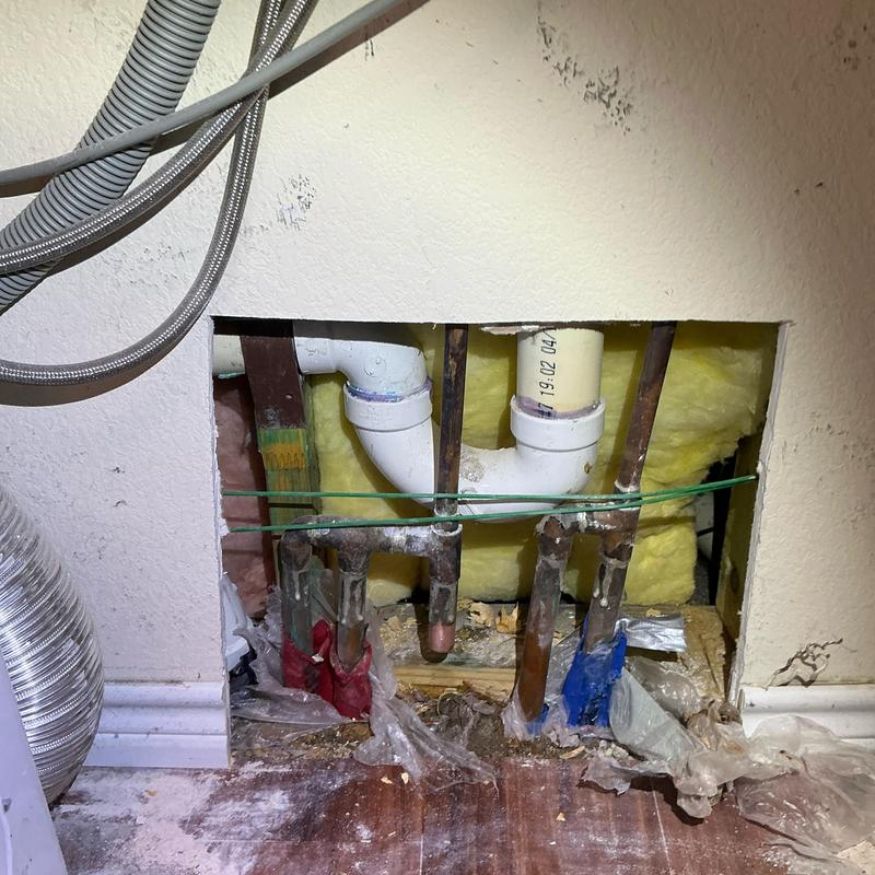 Copper water supply pipes with PVC drain lines inside wall cutout