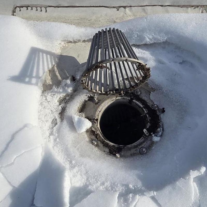 Roof drain pipe with frozen ice blockage on rooftop