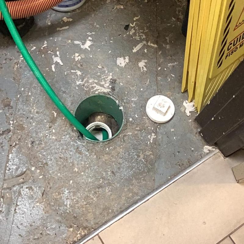 Sump pump pit with green hose inserted