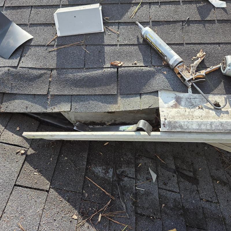 Wall flashing on roof with caulking gun and shingles