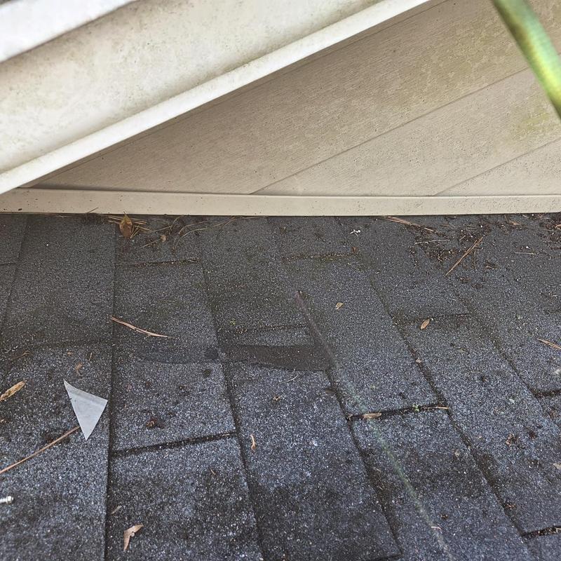 Wall flashing and roof shingles with debris near fascia