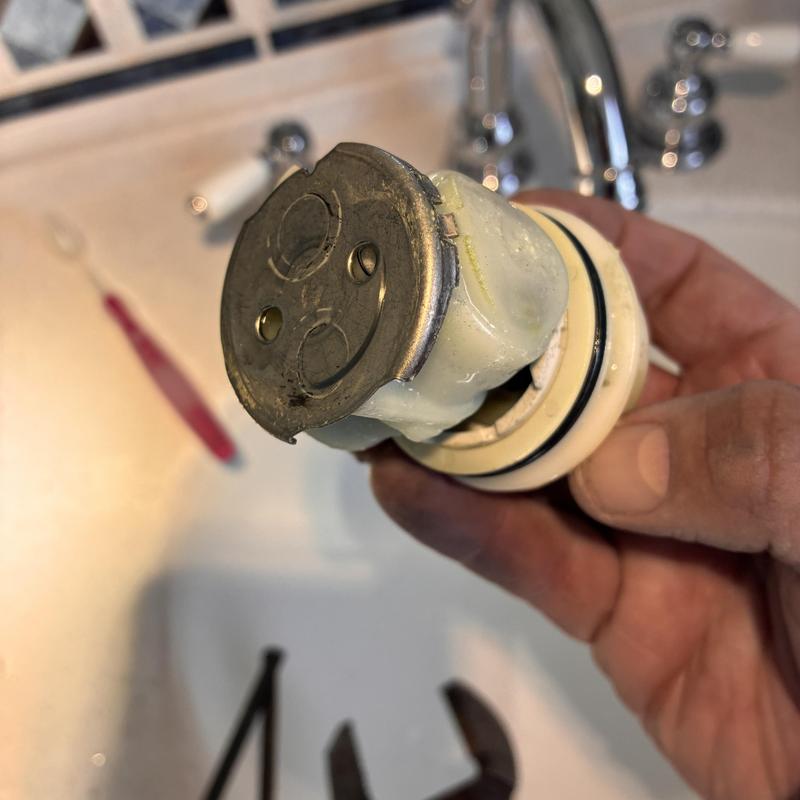 Delta shower cartridge held during replacement in bathroom sink