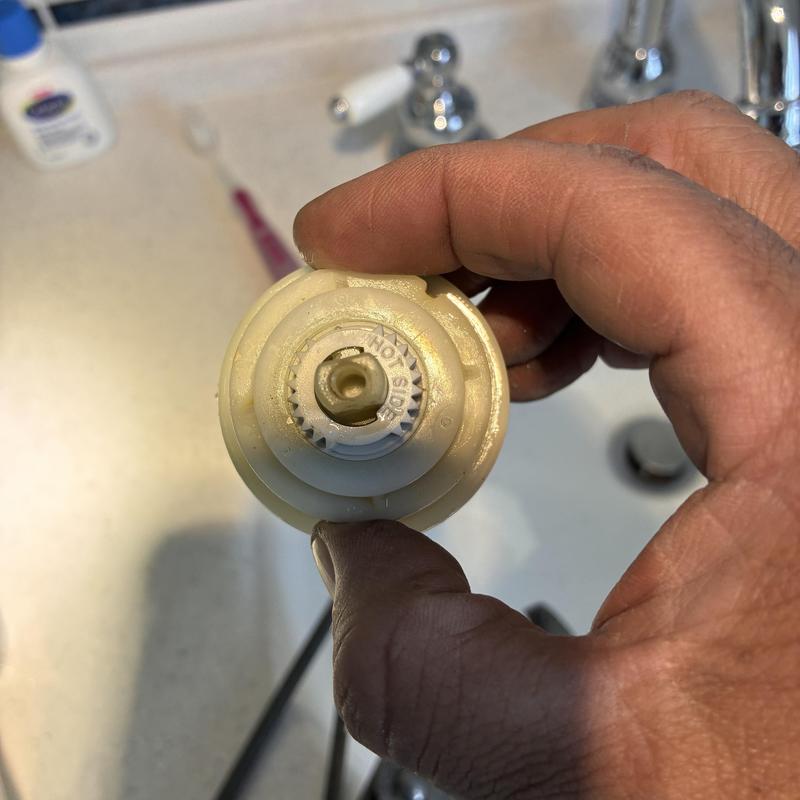 Delta shower cartridge held by hand during repair