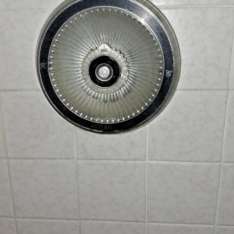 Shower valve handle on tiled wall close-up
