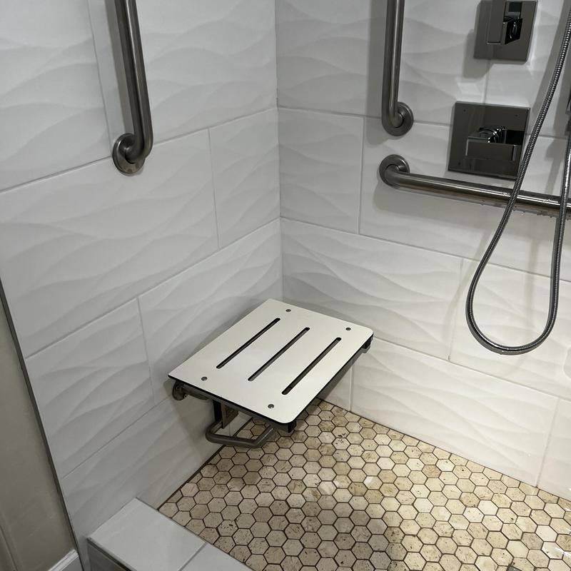 Handicap shower seat with grab bars and tile flooring