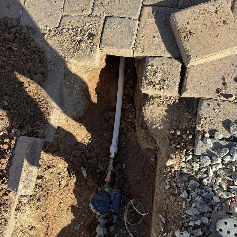 Water main with 1-inch PEX line in trench under pavers