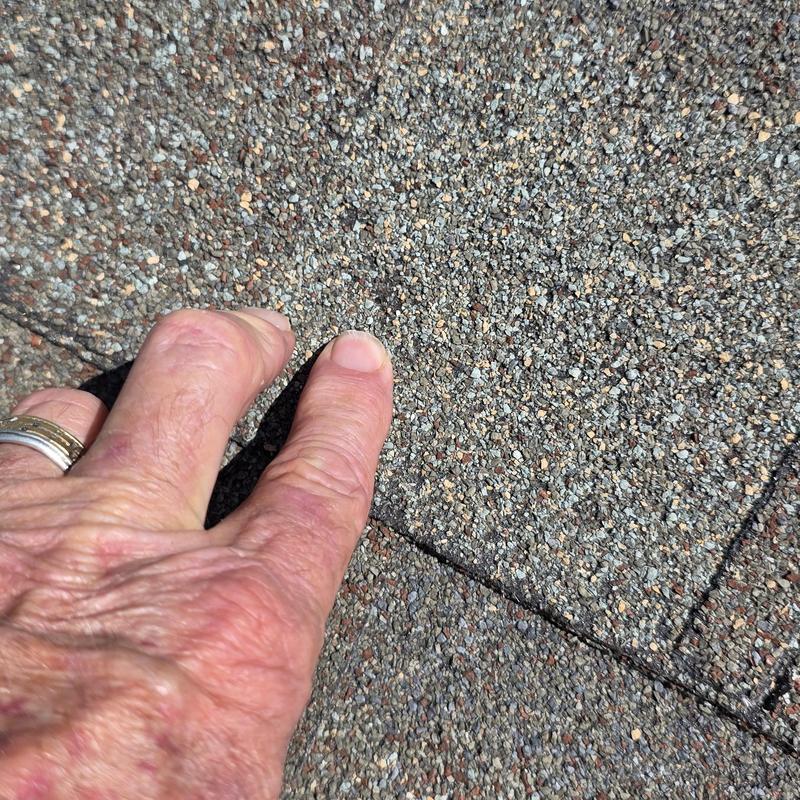 Asphalt shingle surface with wind and hail damage close-up