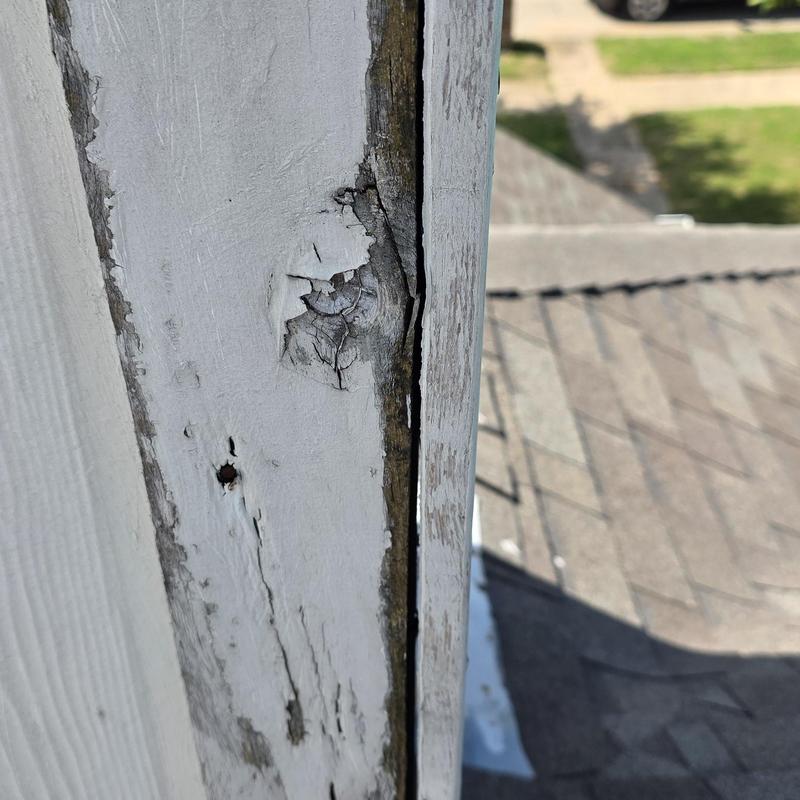 Wooden fascia board damage and paint peeling on roof edge