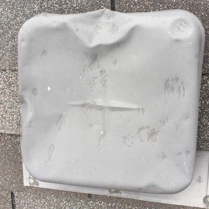 Metal vent cover with visible dents on roof shingles