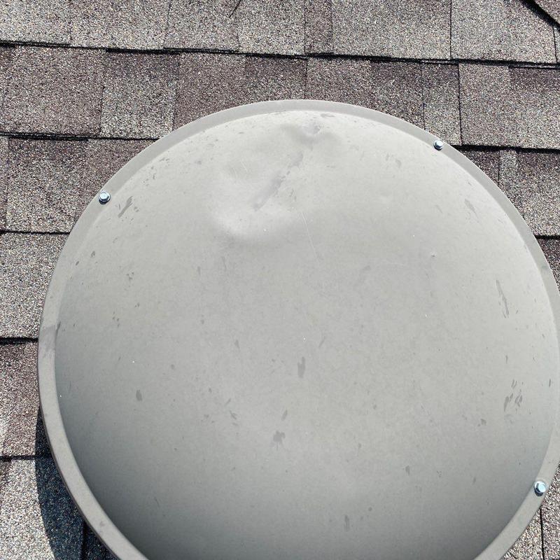 Satellite dish with hail impact dents on roof shingles