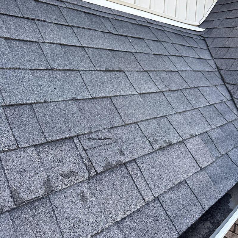 Asphalt shingles with visible hail damage on roof surface