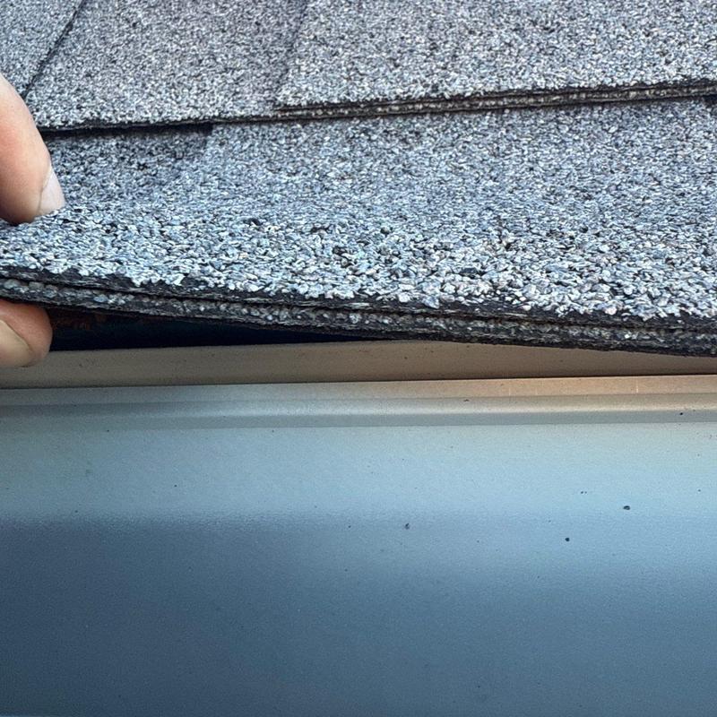 Asphalt shingles lifted showing roof edge gap