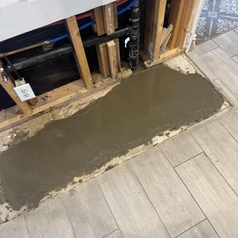 Kitchen sewer line with fresh concrete patch