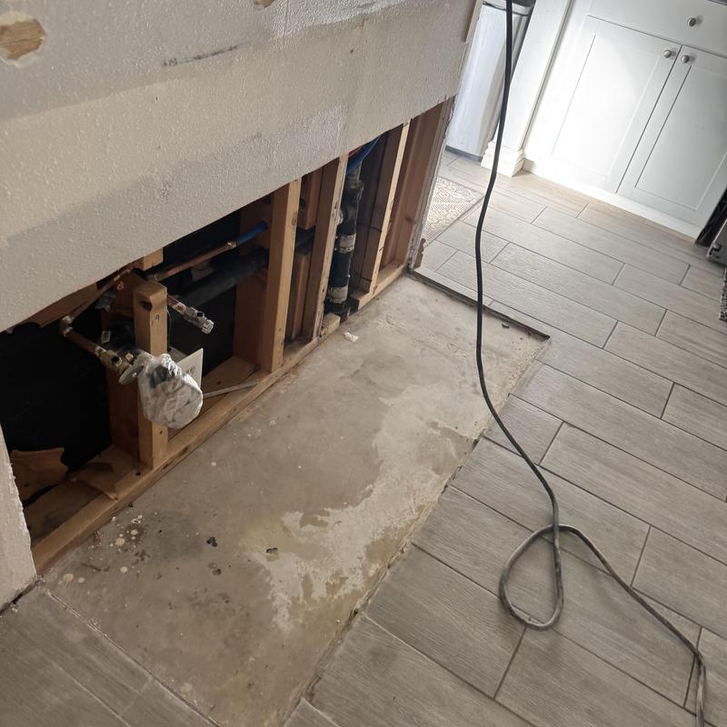 Kitchen sewer line with exposed plumbing and tile floor