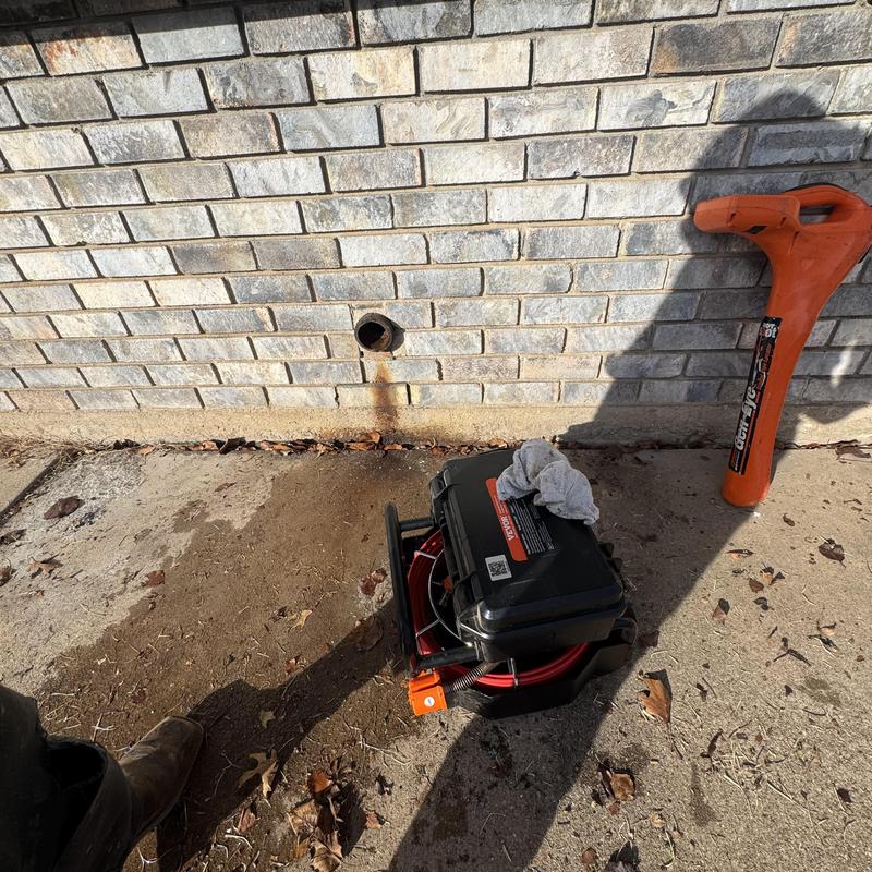 Cast iron kitchen drain pipe and plumbing tools outside wall