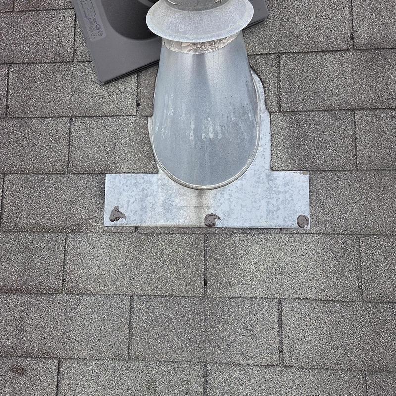 Metal pipe boot on shingled roof with caulking