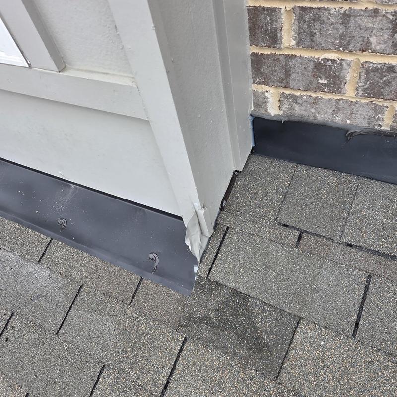 Wall flashing on shingled roof near brick wall