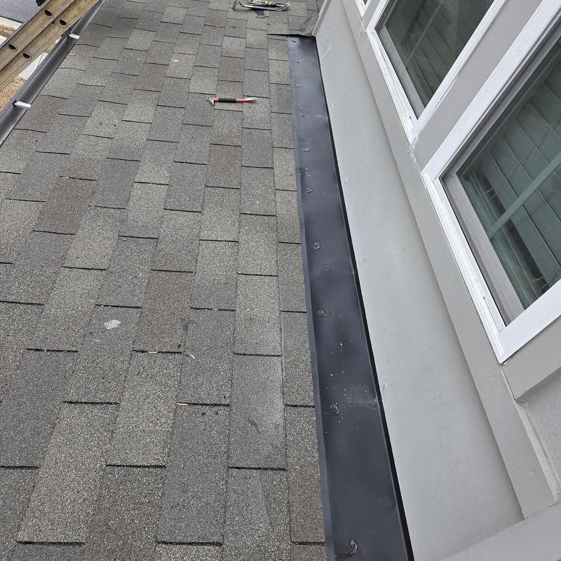 Wall flashing along shingle roof by window installation