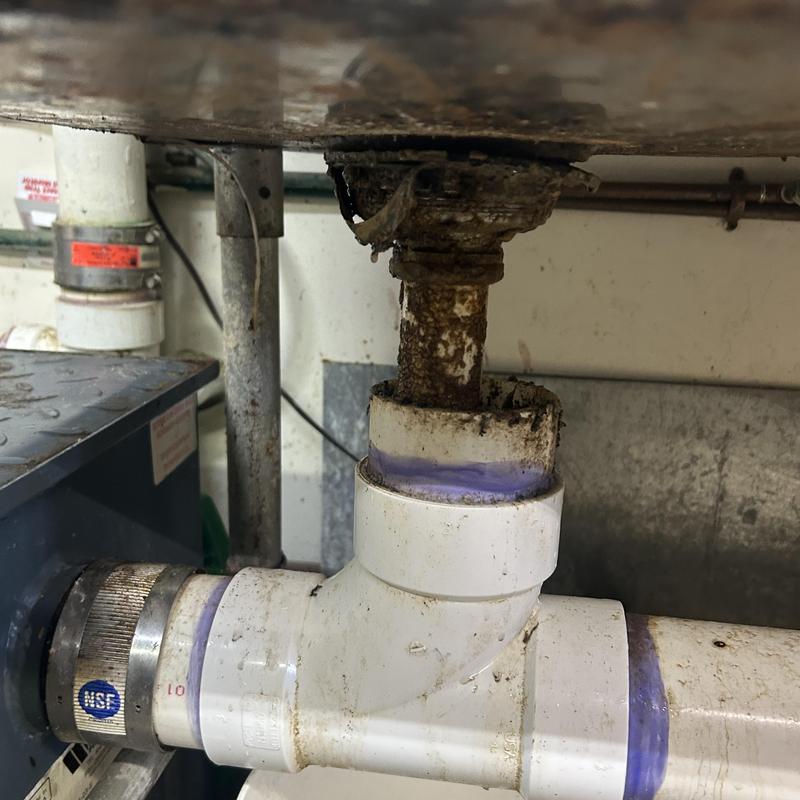 Kitchen sink drain pipe with grease buildup under sink