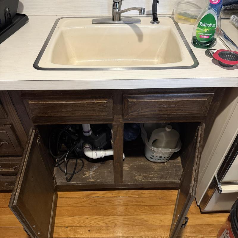 Kitchen sink drain pipes under cabinet with opened doors
