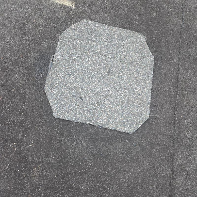 Torch down roofing patch on black roof surface