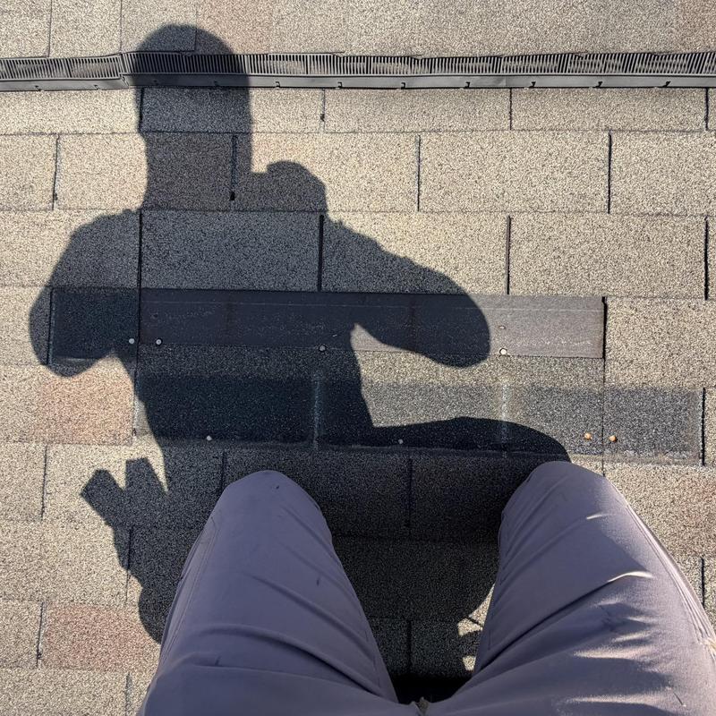 Roof shingles with new replacement and shadow visible