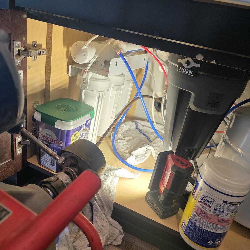 Kitchen sink drain snake tool clearing blockage under cabinet