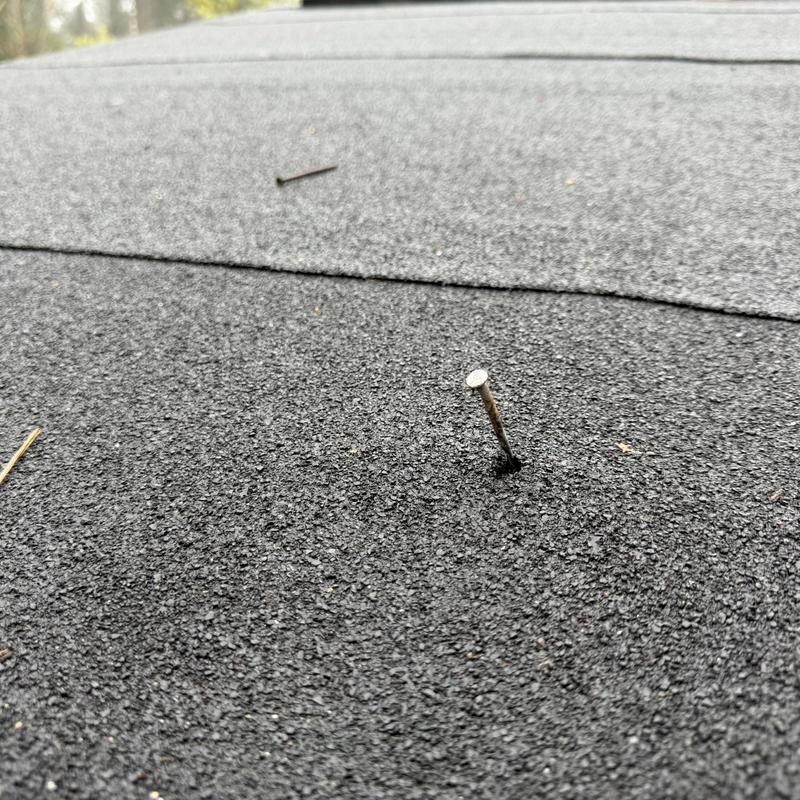 Roof shingles with a popped nail and slight lifting