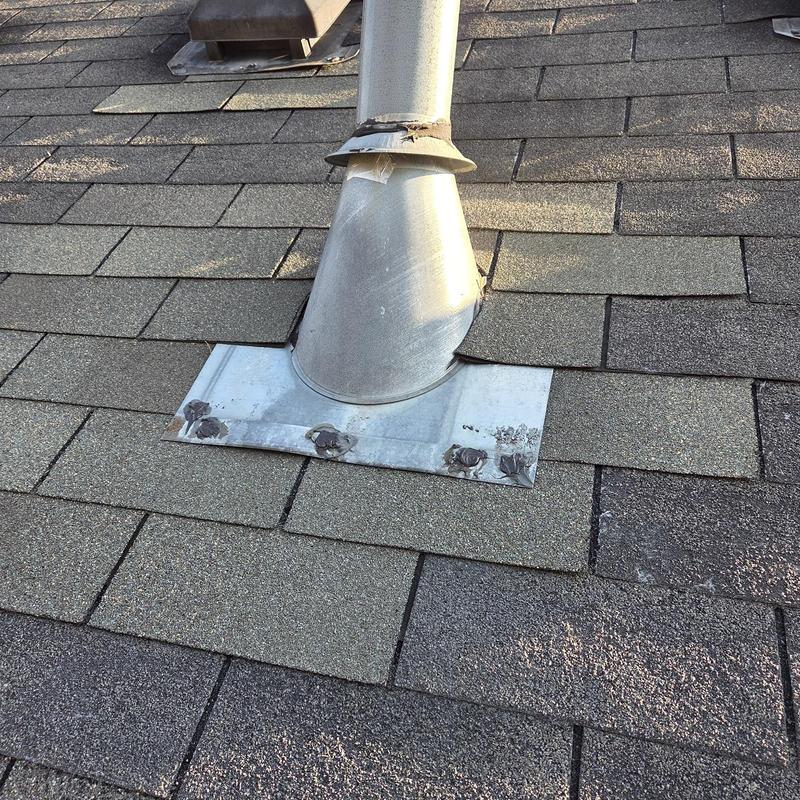 Roof pipe flashing with damaged shingles and caulked seams