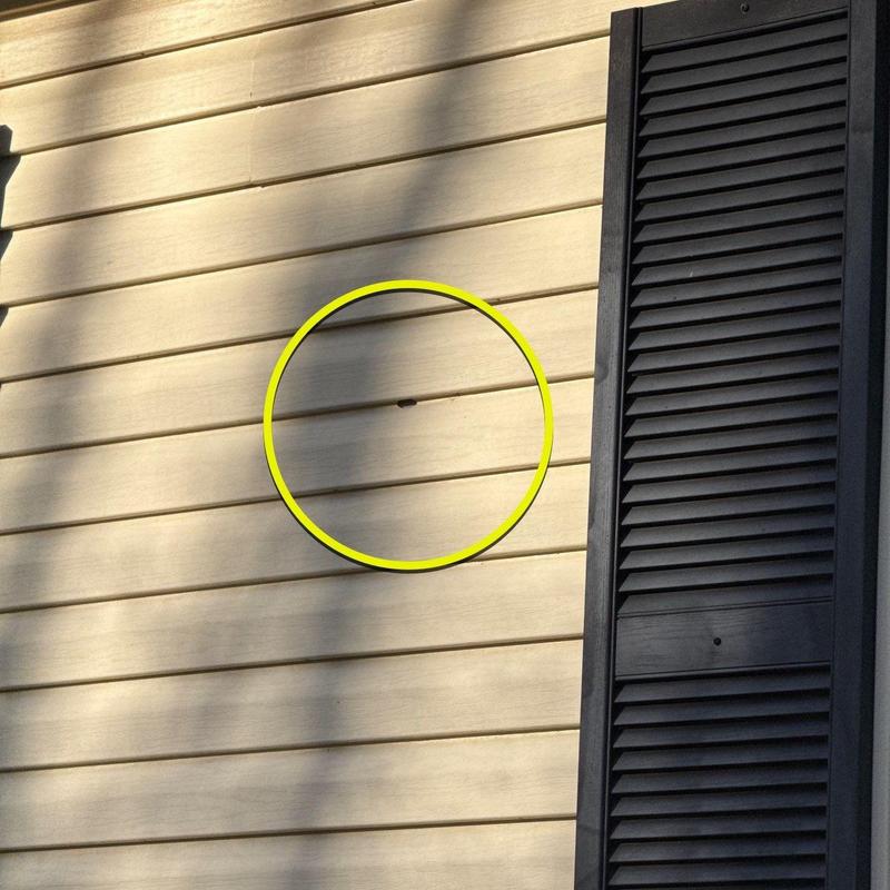 Vinyl siding hole damage marked with yellow circle