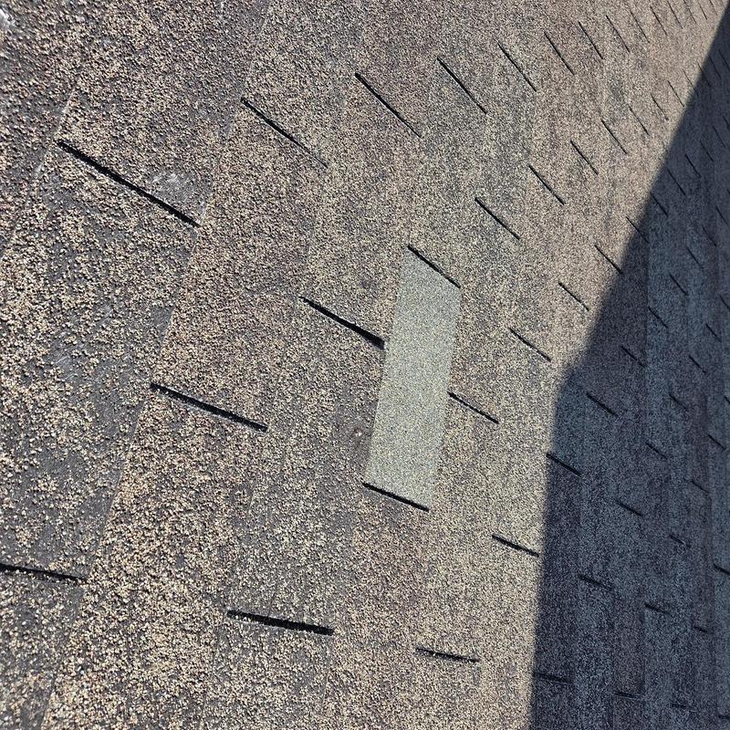Roof shingles with one replaced shingle visible