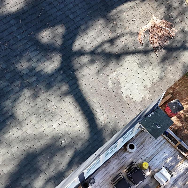 Asphalt shingle roof with debris and shadow above deck
