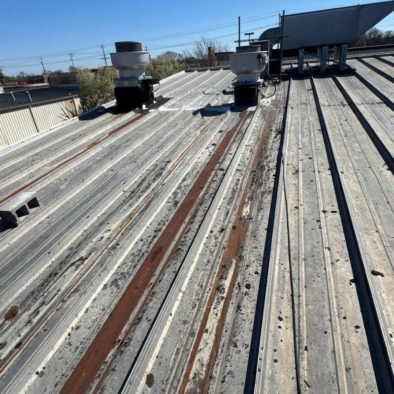 Metal commercial roof panels with rust and hail damage