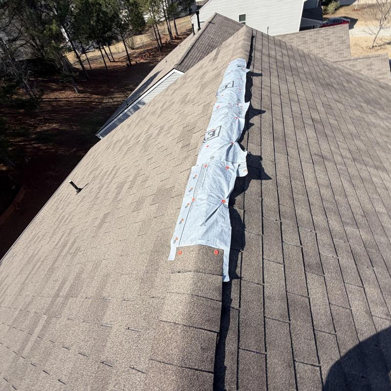 Ridge vent with tarp installed on two-story roof