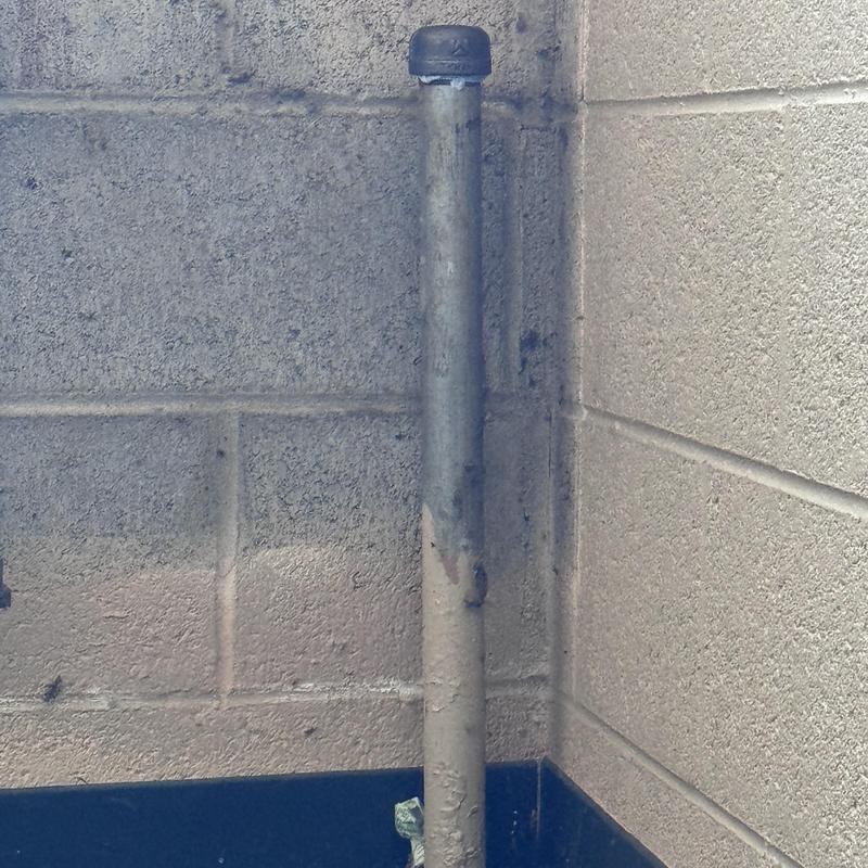 Baseboard heater pipe capped on concrete wall corner