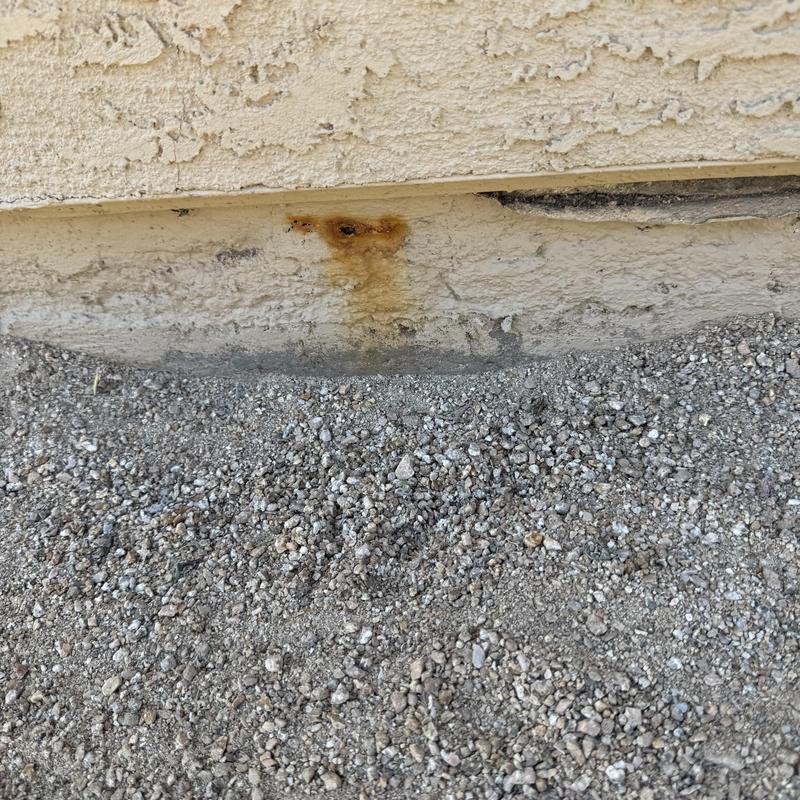 Roman tub exterior wall with rust stain on stucco siding