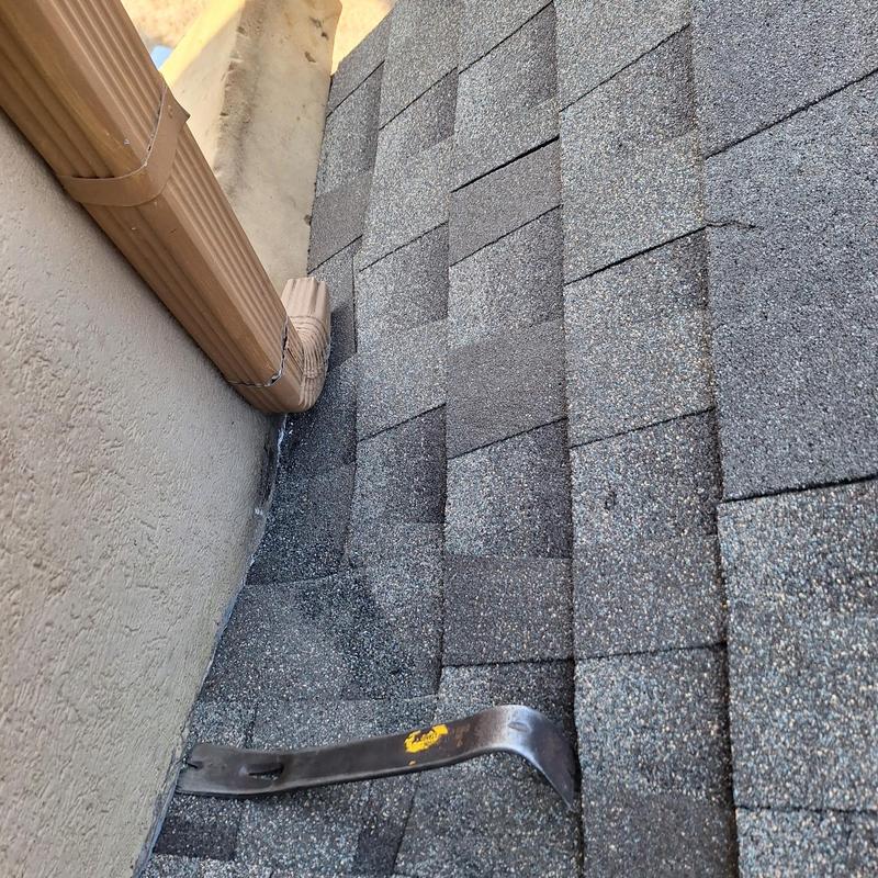 Roof flashing and shingles near downspout on flat roof