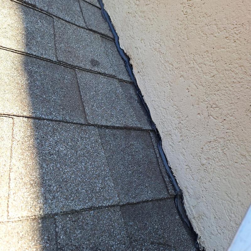 Roof flashing and shingles along stucco wall