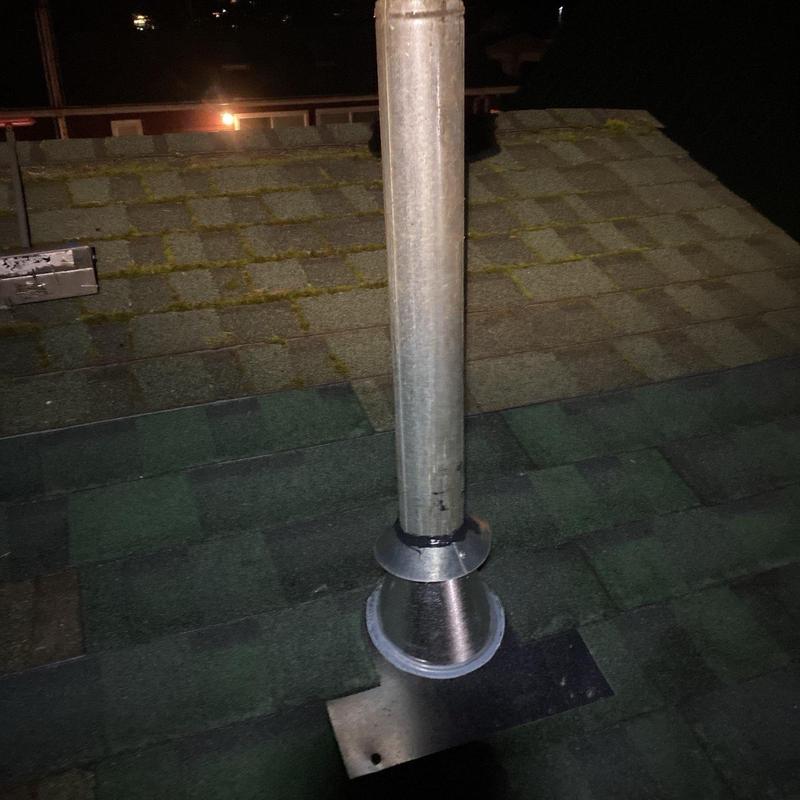 Metal roof vent pipe flashing on shingle roof at night